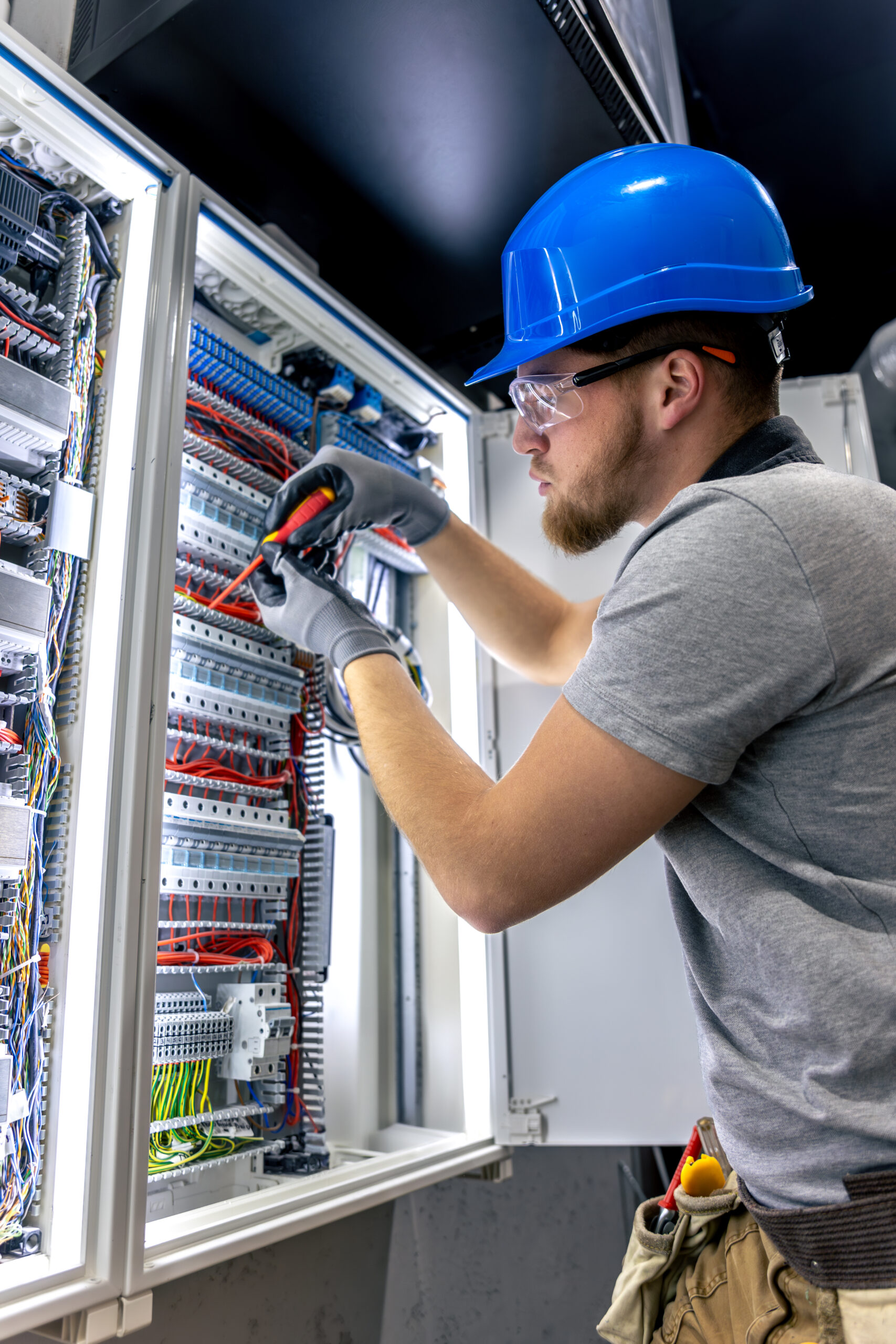 male electrician in uniform working in a switchboard. electricity.