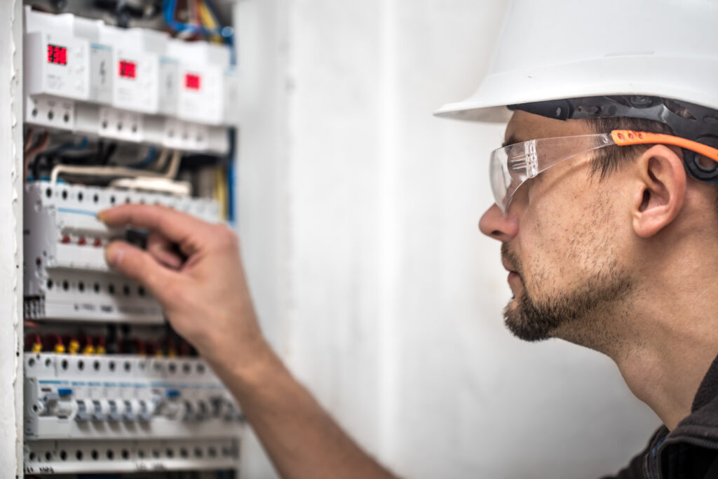 man electrical technician working switchboard with fuses installation connection electrical equipment close up