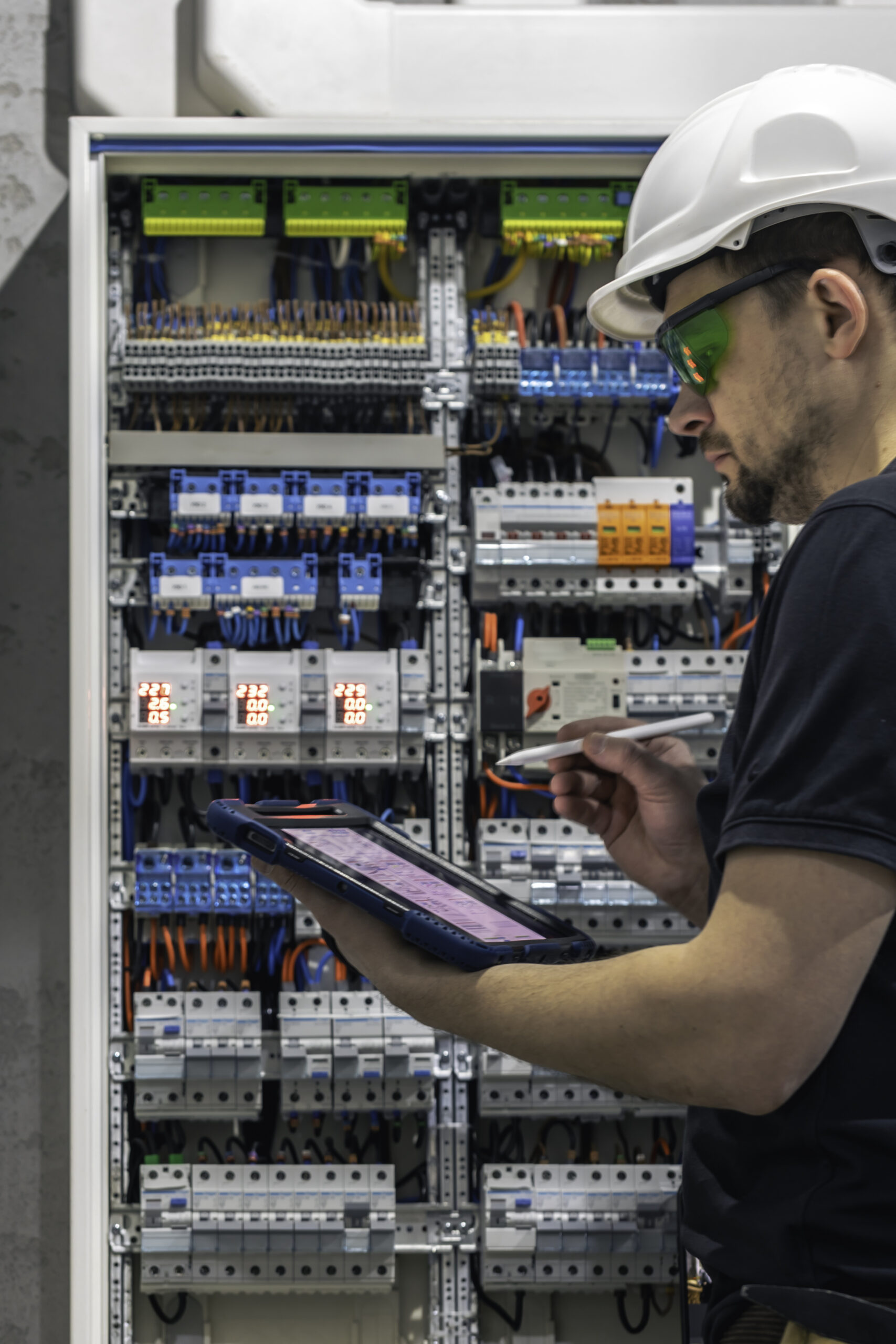 man electrical working switchboard with fuses uses tablet